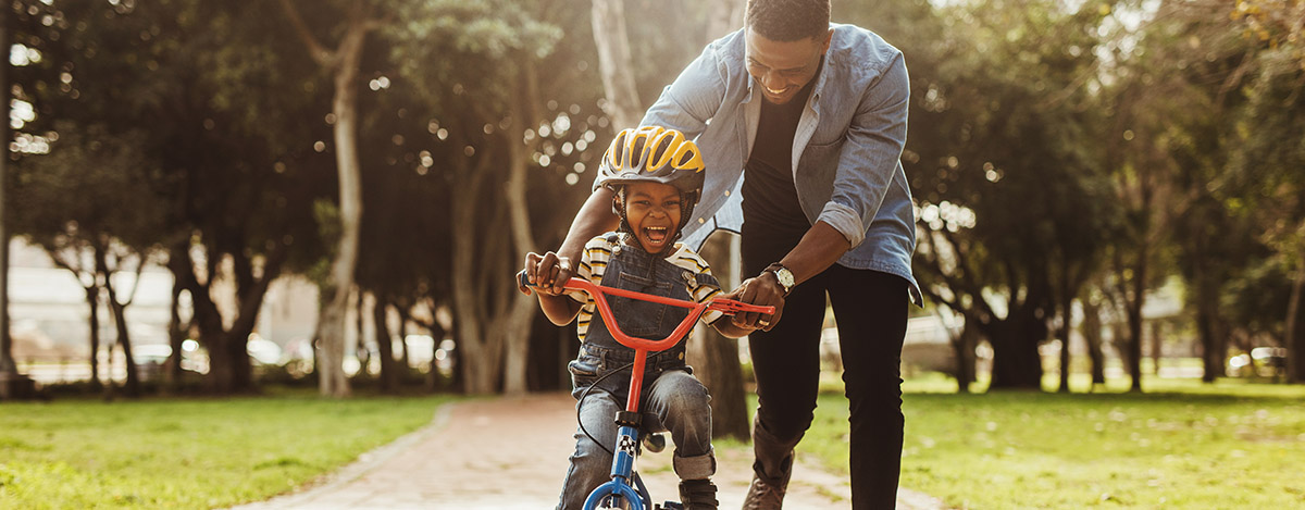 Father and son having fun on a bicycle knowing he's protected 